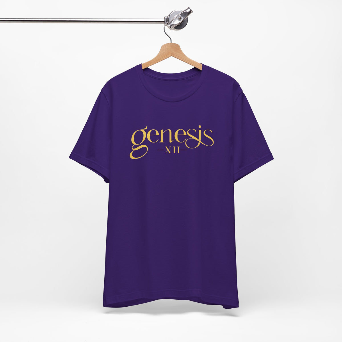 A purple short-sleeve t-shirt hanging on a wooden hanger from a metal clothing rack, featuring the text 'genesis XII' printed in gold across the chest.