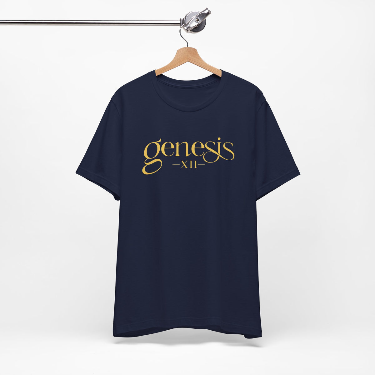 A navy blue short-sleeve t-shirt hanging on a wooden hanger from a metal clothing rack, featuring the text 'genesis XII' printed in gold across the chest.